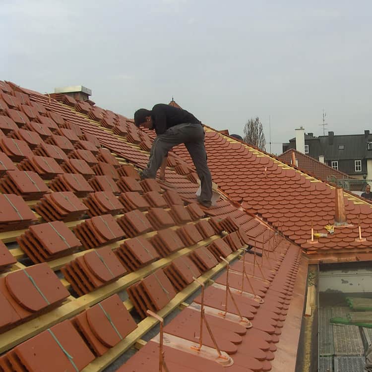 Dachdeckerei München Dachdecker am Dach beim Verlegen von Biberschwanzziegel auf die Dachlattung