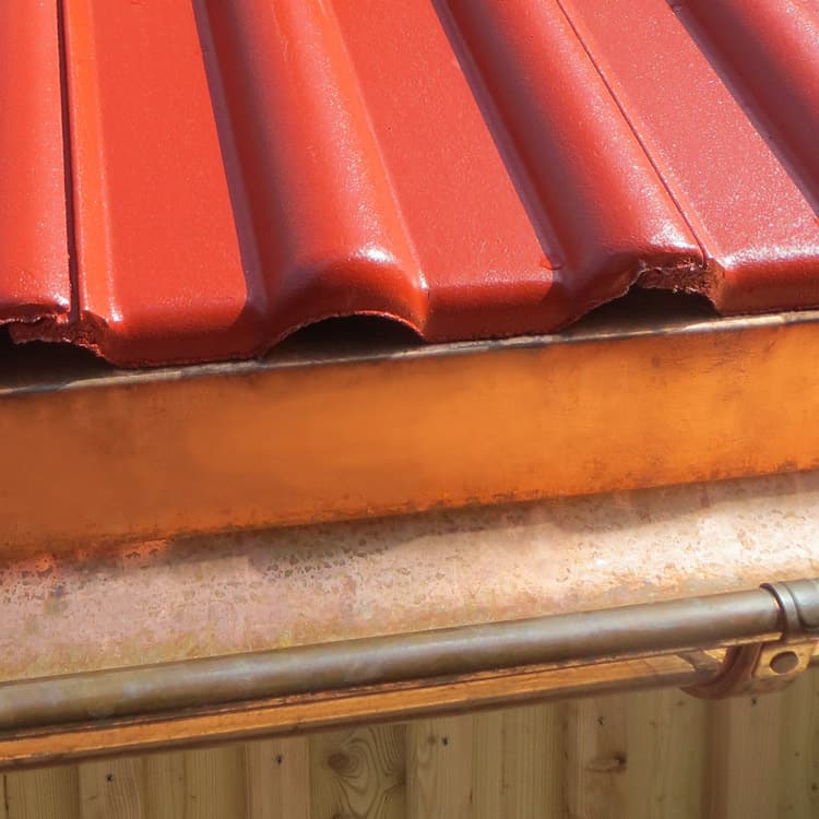 Spengler München Ausschnitt von Dach mit Braas Dachsteine rot und Dachrinne aus Kupfer
