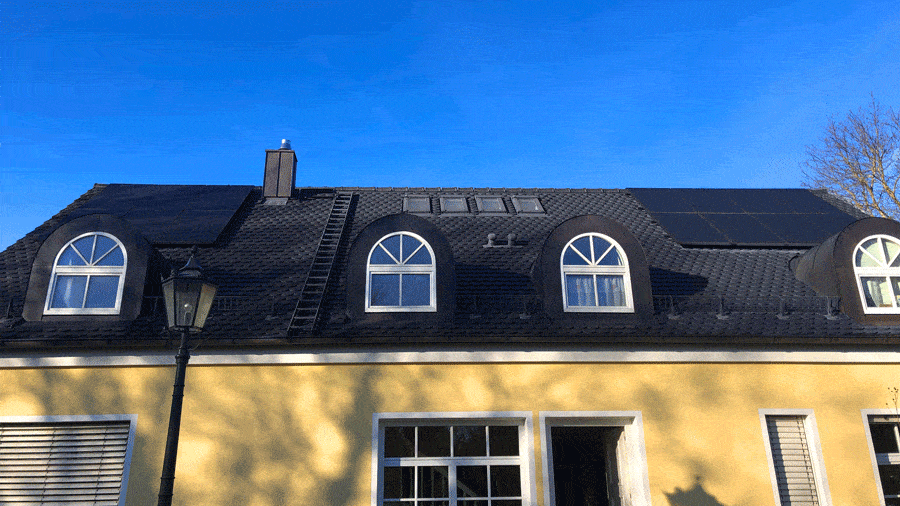 Dachdecker München Schieferdach mit Dachgauben Dachleiter auf gelbem Haus mit tiefblauem Himmel