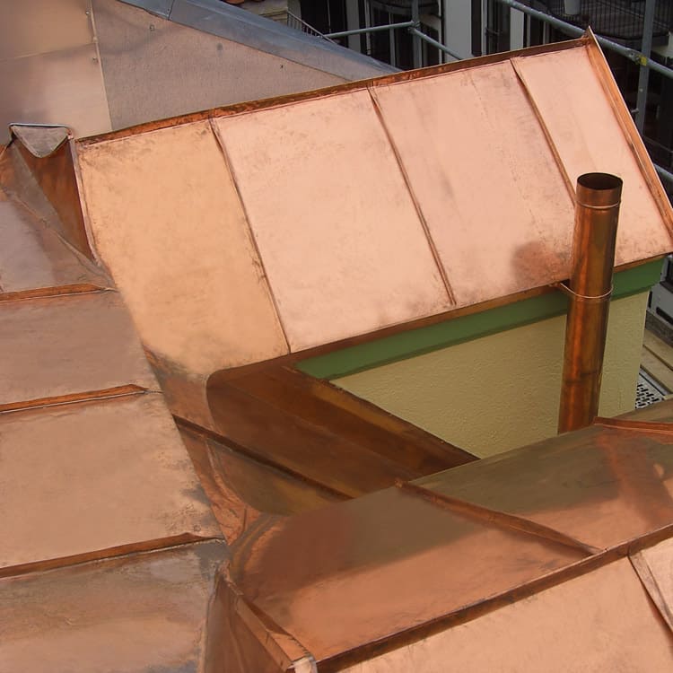 Spengler München verwinkeltes Kupferblechdach mit Stehfalztechnik und Ablaufrohr in Kupfer
