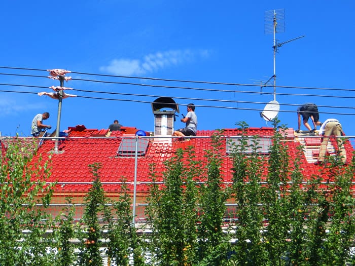 Dachdecker München Dachdecker Spengler Arbeiten an Ziegeldach mit Dachfenster Bäumen mit Himmel
