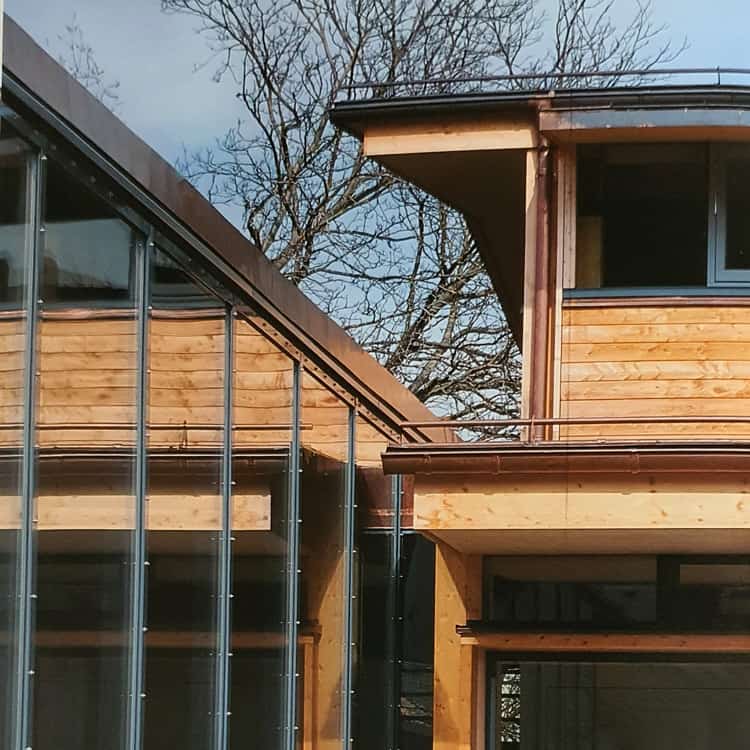 Dachdeckerei München Gebäude mit Holzfassade mit Kupferdachrinne Ablaufrohr Kupferverkleidung
