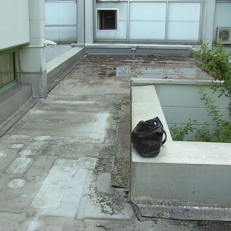 Dachdeckerei München Innenhof Terrasse mit Wasserflächen auf Umrandung schwarze Handtasche