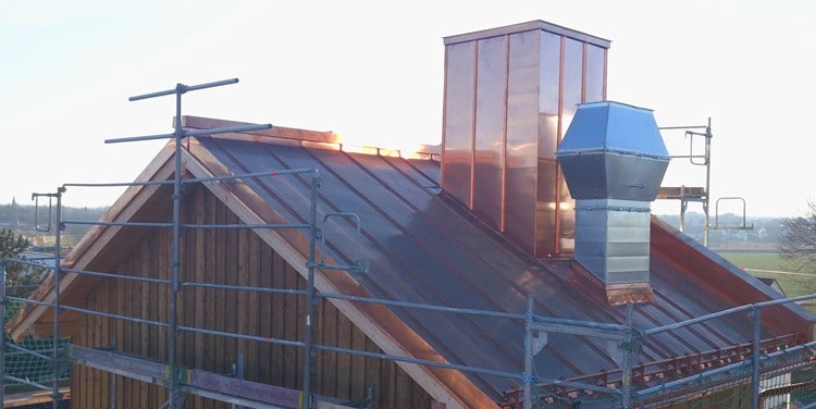 Leistungen Dach: Kupferblechdach mit passgenauer Kamineinfassung und Gerüst an der Giebelseite für sichere Montage