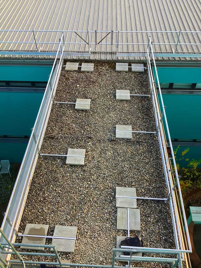 Blick auf den gesicherten Zugang mit Kiesschüttung und montierten Seitensturzgeländern am Flachdachbau in München
