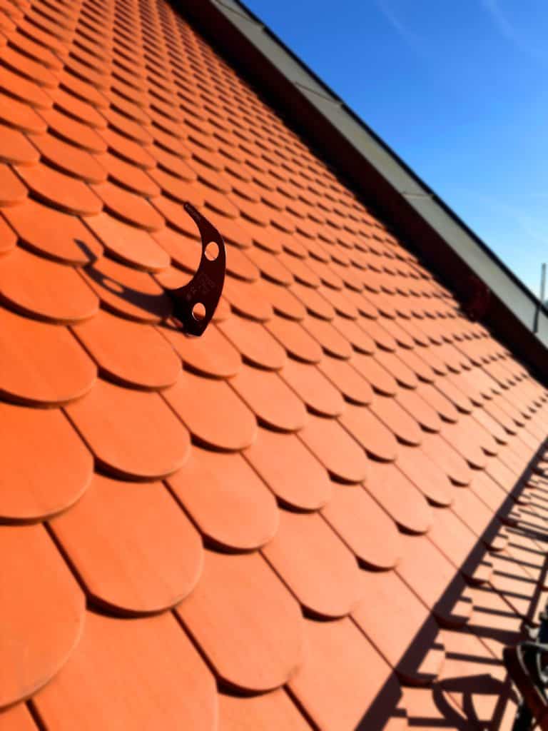 Dachhaken als Anschlagpunkt auf Biberschwanzziegel-Steildach für Dachsicherheit München in Nahaufnahme