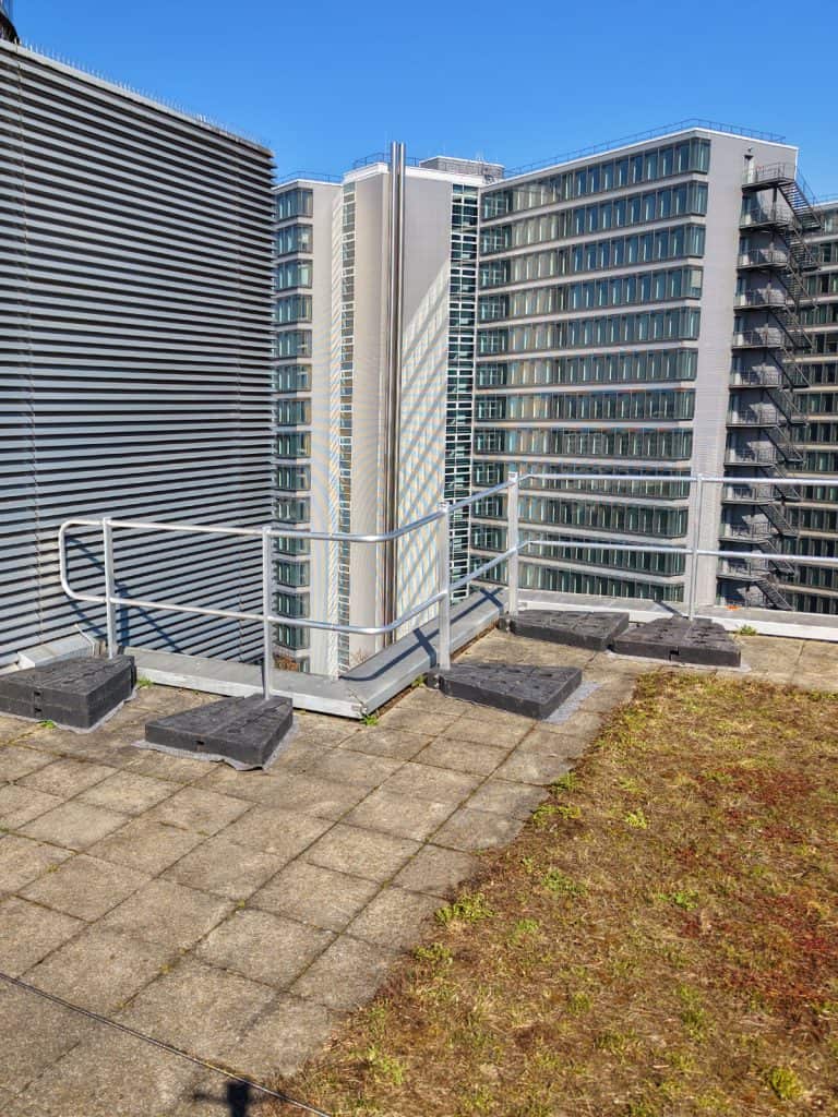 Eckausführung eines Seitensturzgeländers auf begrüntem Flachdach für Dachsicherheit München mit Hochhäusern