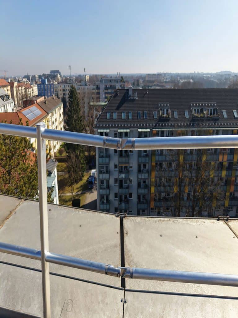 Verbindungsstücke des montierten Seitensturzgeländers auf Flachdach für Dachsicherheit München vor Mehrfamilienhaus