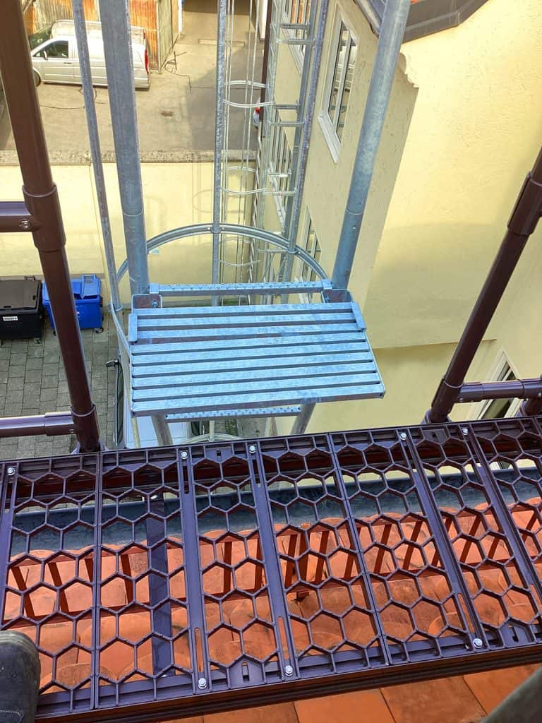 Nahaufnahme eines Laufsteggitters mit Absturzgeländer am Zugang über Feuerleiter auf das Steildach in München