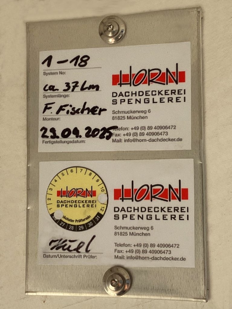 Wartungskontrollplaketten von Firma Horn für Dachsicherheitssysteme mit Prüfdatum an Metallplatte montiert