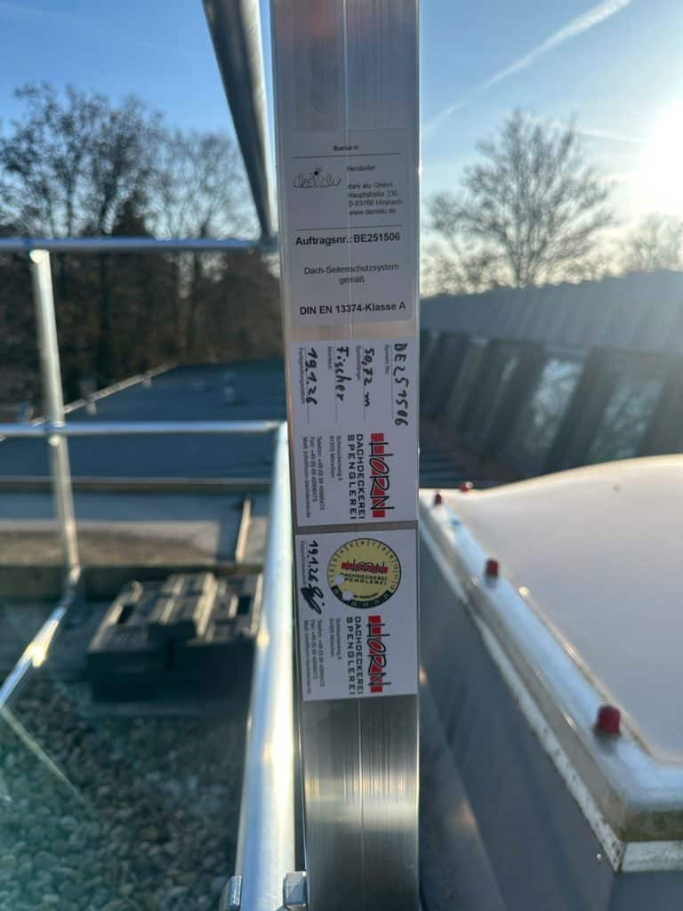 Nahaufnahme einer Wartungsplakette von Firma Horn auf montiertem Seitensturzgeländer in München